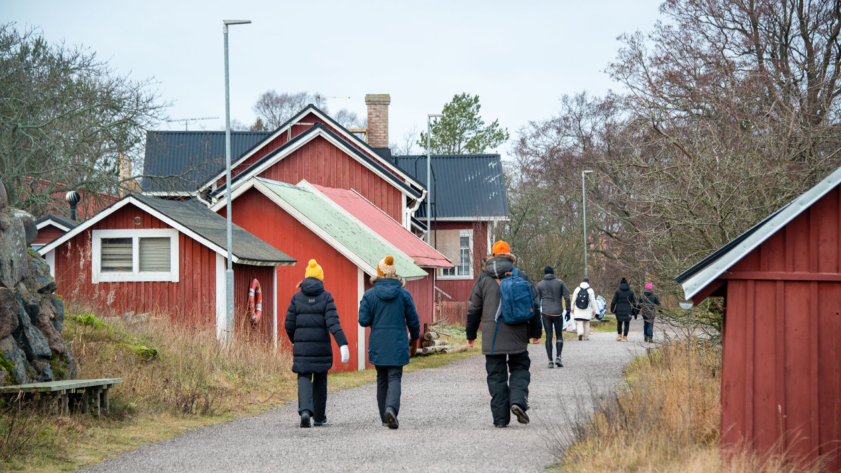 Ihmiset kävelemässä hiekkatiellä saaristokylässä