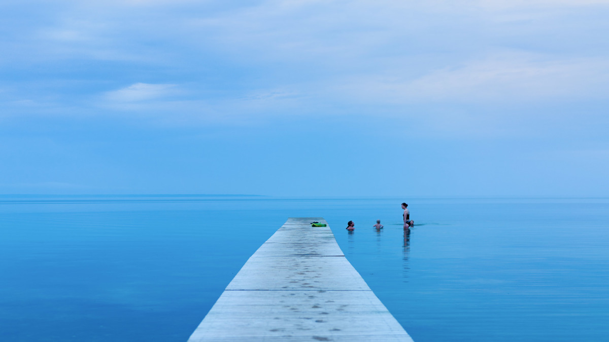 Kaksi lasta ja aikuinen uimassa Itämerellä. 