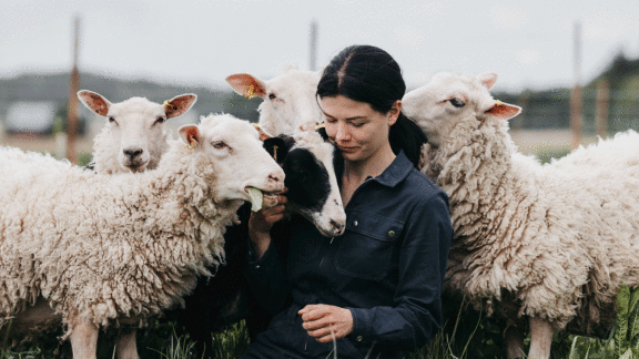 Viljelijä Marja Oesch tilallaan lampaiden kanssa