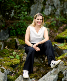 Petra Gräsbeck istuu kivellä sammaleisessa metsässä.