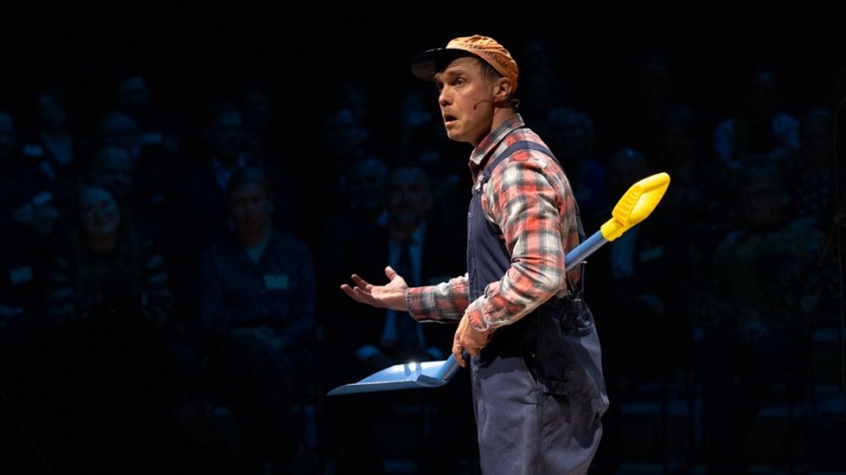 Näyttelijä maanviljelijän vaatteissa ja lapio kädessä lavalla esittää monologia.