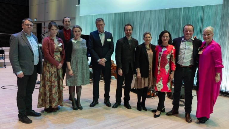 Kymmenen ihmistä seisoo vierekkäin lavalla.