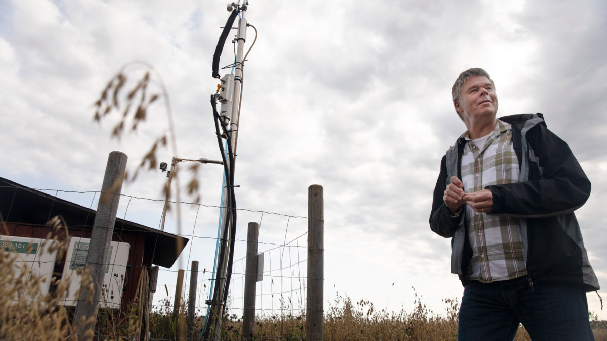 Tutkimusprofessori Jari Liski pellolla Pellolle pystytetty eddy covariance -teknologiaa edustavan laitteen kanssa