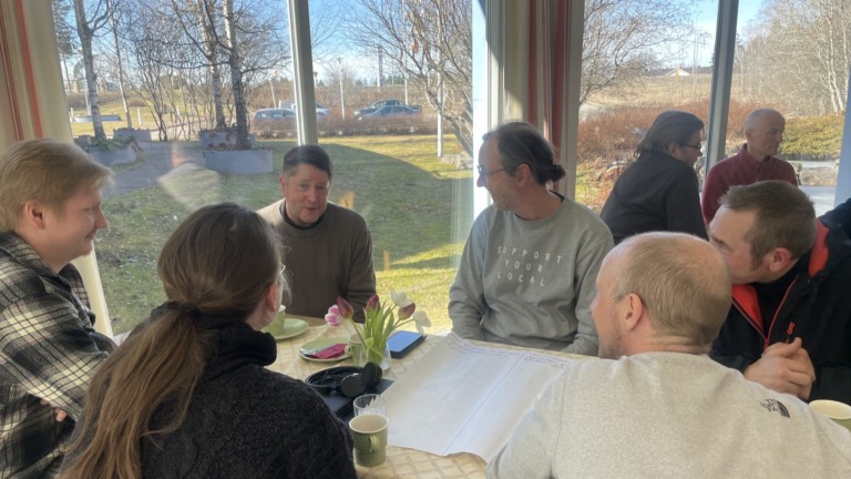 Työpajan osallistujia pöydän ääressä kesksutelemassa.