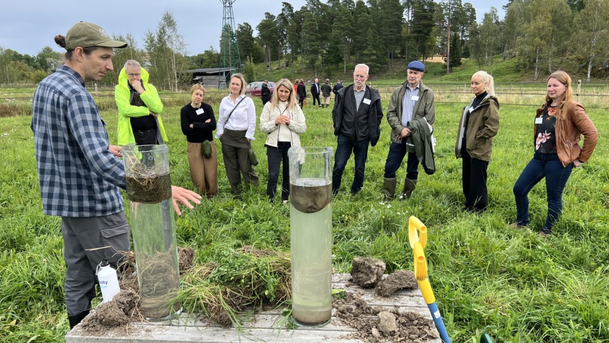 Ihmisiä seuraa viljelijän esitelmää maan tiivistymistä pellolla.