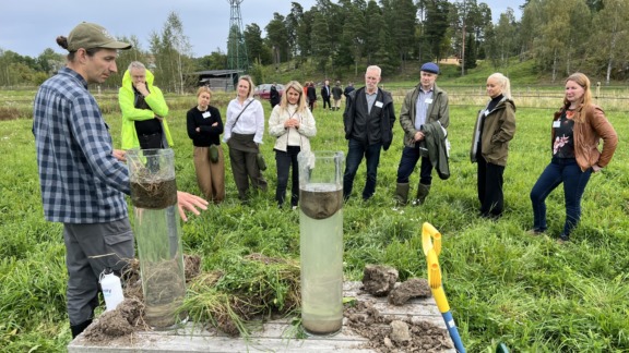 Ihmisiä seuraa viljelijän esitelmää maan tiivistymistä pellolla.